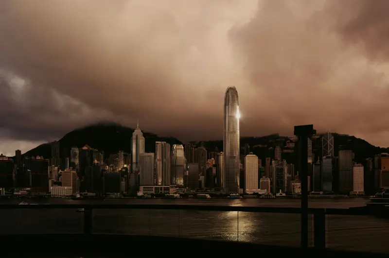 Hongkongs silhuett med höga skyskrapor speglad över Victoria Harbour i skymningen