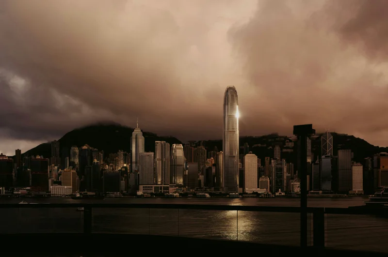 Hongkongs silhuett med höga skyskrapor speglad över Victoria Harbour i skymningen